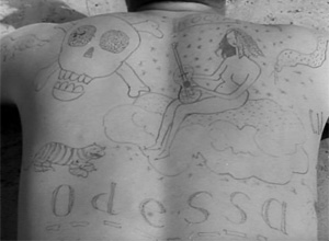 Татуировка на спине: русалка с гитарой, череп и кости, тигра, удав, надпись "Odessa" и пр.